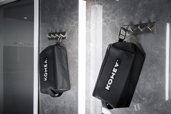 Komean toilettilaukku roikkumassa kylpyhuoneen koukussa, karabiiniin kiinnitettynä.